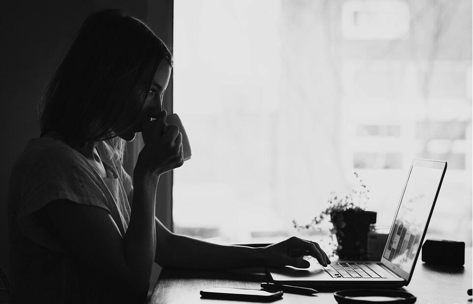 Une femme buvant un café qui trie des agences immobilières en ligne